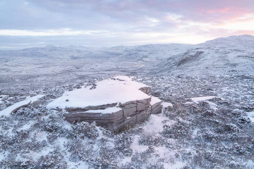 At sunrise, snow rests on an outcrop of Torridonian sandstone at the foot of Quinag. The view is looking away from Quinag towards the hills of North West Sutherland National Scenic Area.